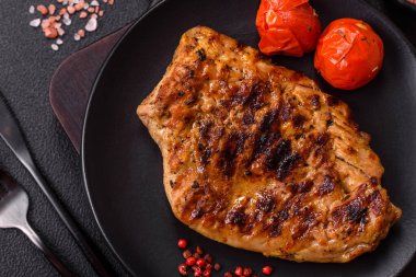 Izgarada pişirilmiş leziz domuz eti. Koyu beton arka planda tuz, baharat ve otlarla birlikte.