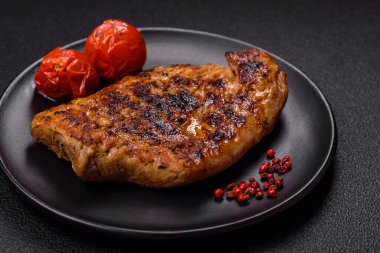 Izgarada pişirilmiş leziz domuz eti. Koyu beton arka planda tuz, baharat ve otlarla birlikte.