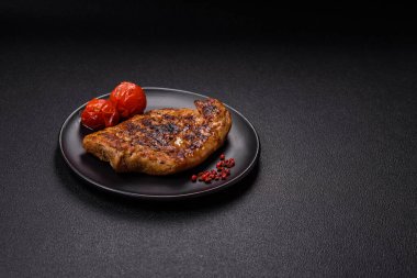 Izgarada pişirilmiş leziz domuz eti. Koyu beton arka planda tuz, baharat ve otlarla birlikte.