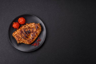 Izgarada pişirilmiş leziz domuz eti. Koyu beton arka planda tuz, baharat ve otlarla birlikte.