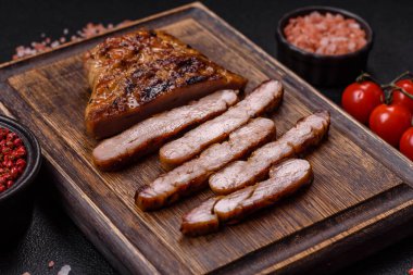 Izgarada pişirilmiş leziz domuz eti. Koyu beton arka planda tuz, baharat ve otlarla birlikte.