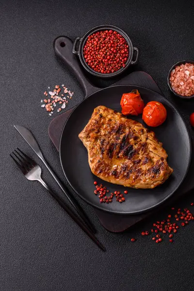 Izgarada pişirilmiş leziz domuz eti. Koyu beton arka planda tuz, baharat ve otlarla birlikte.