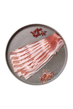 Beyaz arka planda baharat ve otlarla dilimlenmiş taze çiğ domuz pastırması.