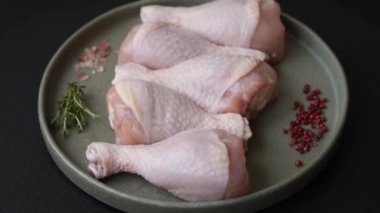 Çiğ tavuk budu, tuz, baharat ve pişirmeye hazır bitkiler.