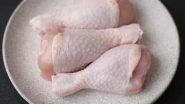 Çiğ tavuk budu, tuz, baharat ve pişirmeye hazır bitkiler.