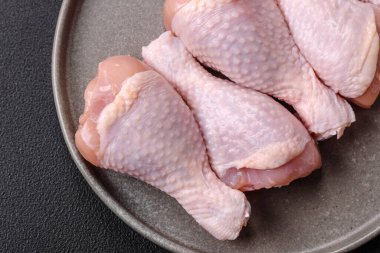 Çiğ tavuk budu, tuz, baharat ve pişirmeye hazır bitkiler.