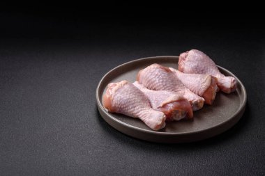 Çiğ tavuk budu, tuz, baharat ve pişirmeye hazır bitkiler.