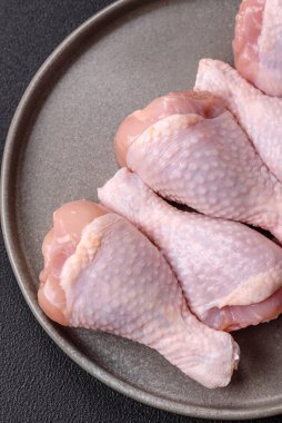 Çiğ tavuk budu, tuz, baharat ve pişirmeye hazır bitkiler.