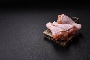 Çiğ tavuk budu, tuz, baharat ve pişirmeye hazır bitkiler.