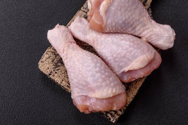 Çiğ tavuk budu, tuz, baharat ve pişirmeye hazır bitkiler.