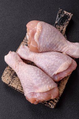 Çiğ tavuk budu, tuz, baharat ve pişirmeye hazır bitkiler.