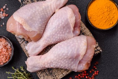 Çiğ tavuk budu, tuz, baharat ve pişirmeye hazır bitkiler.