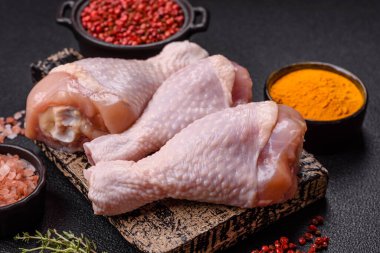 Çiğ tavuk budu, tuz, baharat ve pişirmeye hazır bitkiler.