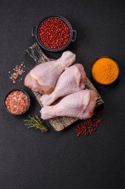 Çiğ tavuk budu, tuz, baharat ve pişirmeye hazır bitkiler.