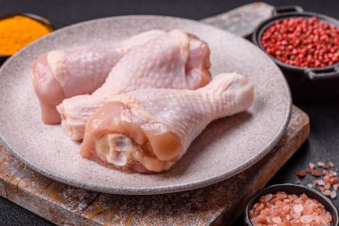 Çiğ tavuk budu, tuz, baharat ve pişirmeye hazır bitkiler.