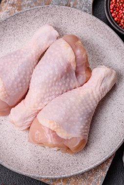 Çiğ tavuk budu, tuz, baharat ve pişirmeye hazır bitkiler.