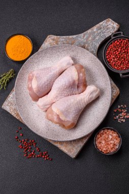 Çiğ tavuk budu, tuz, baharat ve pişirmeye hazır bitkiler.