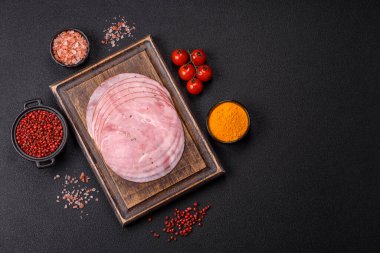 Tuzlu, baharatlı ve otlu füme jambon koyu dokulu arka planda yuvarlak dilimler halinde kesilmiş.