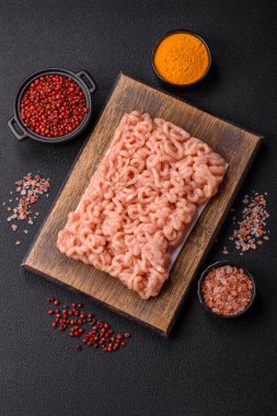 Koyu beton arka planda tuzlu, baharatlı ve otlu çiğ tavuk.