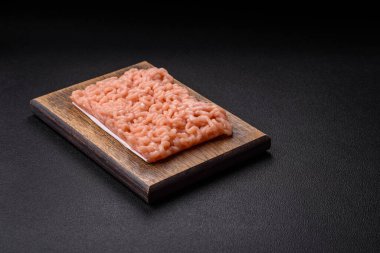 Koyu beton arka planda tuzlu, baharatlı ve otlu çiğ tavuk.