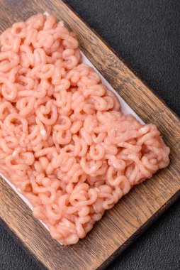 Koyu beton arka planda tuzlu, baharatlı ve otlu çiğ tavuk.