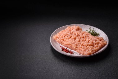 Koyu beton arka planda tuzlu, baharatlı ve otlu çiğ tavuk.