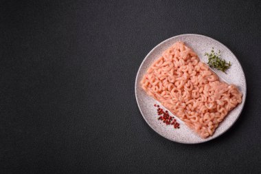 Koyu beton arka planda tuzlu, baharatlı ve otlu çiğ tavuk.