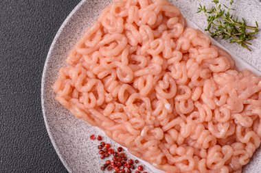 Koyu beton arka planda tuzlu, baharatlı ve otlu çiğ tavuk.