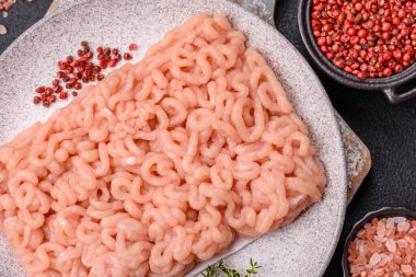 Koyu beton arka planda tuzlu, baharatlı ve otlu çiğ tavuk.