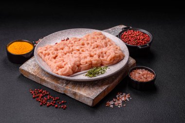 Koyu beton arka planda tuzlu, baharatlı ve otlu çiğ tavuk.