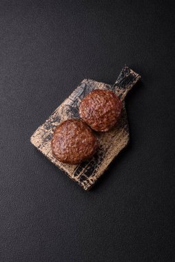 Tuzlu, baharatlı ve otlu sığır burger köfteleri koyu beton arka planda kızartılıyor.