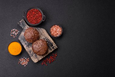 Tuzlu, baharatlı ve otlu sığır burger köfteleri koyu beton arka planda kızartılıyor.
