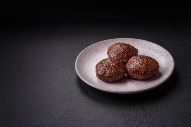 Tuzlu, baharatlı ve otlu sığır burger köfteleri koyu beton arka planda kızartılıyor.