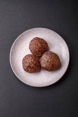 Tuzlu, baharatlı ve otlu sığır burger köfteleri koyu beton arka planda kızartılıyor.