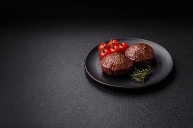 Tuzlu, baharatlı ve otlu sığır burger köfteleri koyu beton arka planda kızartılıyor.