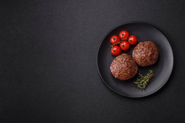 Tuzlu, baharatlı ve otlu sığır burger köfteleri koyu beton arka planda kızartılıyor.