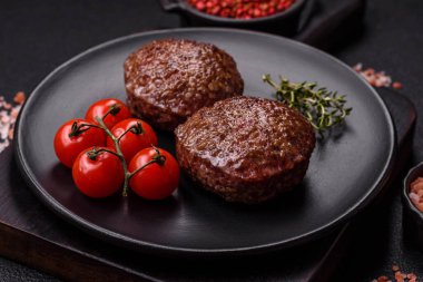 Tuzlu, baharatlı ve otlu sığır burger köfteleri koyu beton arka planda kızartılıyor.