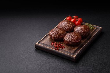 Tuzlu, baharatlı ve otlu sığır burger köfteleri koyu beton arka planda kızartılıyor.