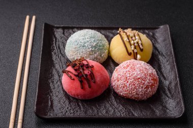 Lezzetli Asya mochi tatlısı pirinç hamuru kabuğu ve koyu beton arka planda meyveler.