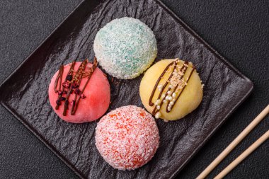 Lezzetli Asya mochi tatlısı pirinç hamuru kabuğu ve koyu beton arka planda meyveler.