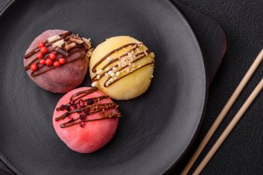 Lezzetli Asya mochi tatlısı pirinç hamuru kabuğu ve koyu beton arka planda meyveler.