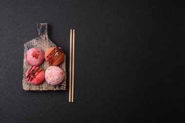 Lezzetli Asya mochi tatlısı pirinç hamuru kabuğu ve koyu beton arka planda meyveler.