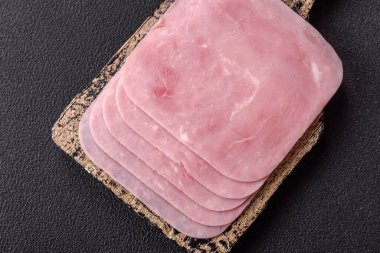 Kaynamış jambon, koyu beton arka planda körili ve baharatlı kare dilimlere bölünmüş.