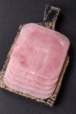 Kaynamış jambon, koyu beton arka planda körili ve baharatlı kare dilimlere bölünmüş.