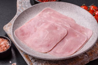 Kaynamış jambon, koyu beton arka planda körili ve baharatlı kare dilimlere bölünmüş.