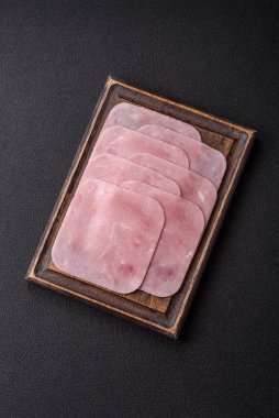 Kaynamış jambon, koyu beton arka planda körili ve baharatlı kare dilimlere bölünmüş.