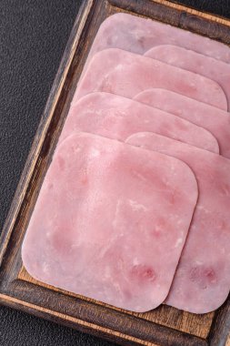 Kaynamış jambon, koyu beton arka planda körili ve baharatlı kare dilimlere bölünmüş.