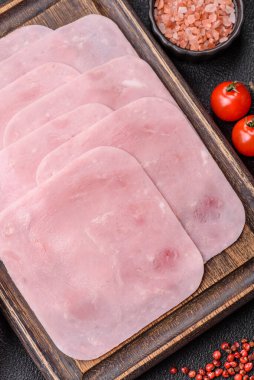 Kaynamış jambon, koyu beton arka planda körili ve baharatlı kare dilimlere bölünmüş.