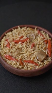 Lezzetli taze pilav, pirinç, havuç, et, soğan, baharat ve böğürtlen ile koyu beton arka planda seramik bir tabakta.