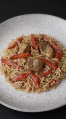 Lezzetli taze pilav, pirinç, havuç, et, soğan, baharat ve böğürtlen ile koyu beton arka planda seramik bir tabakta.